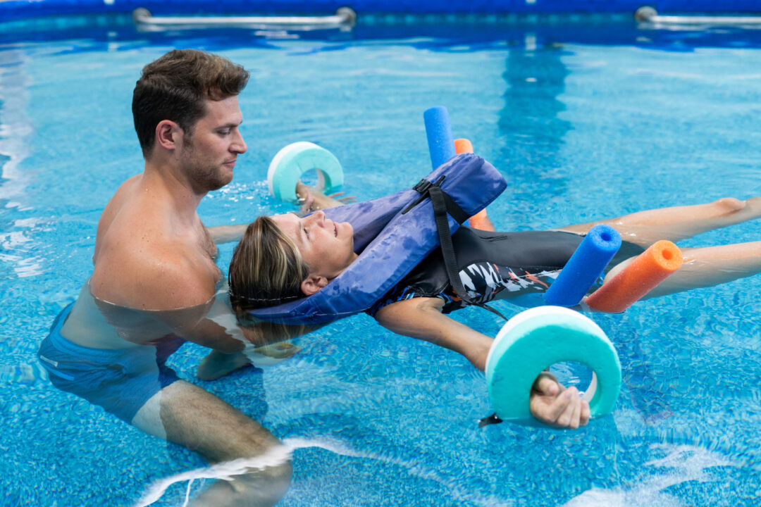 a man providing aquatic physical therapy to a woman in a swimming pool