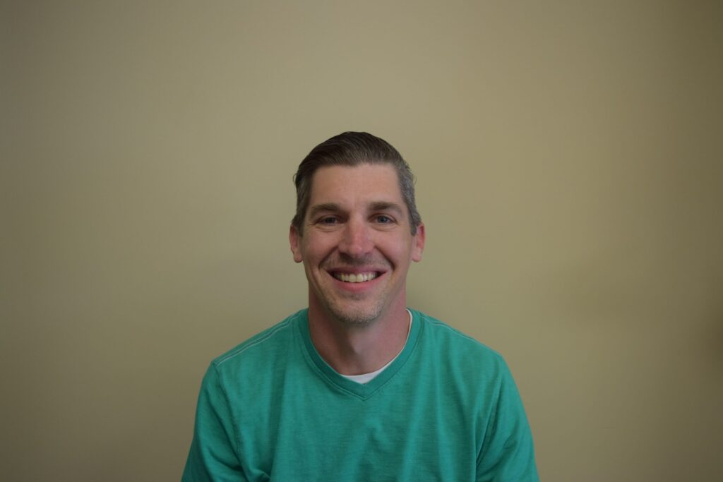 a man in a green shirt smiling for the camera