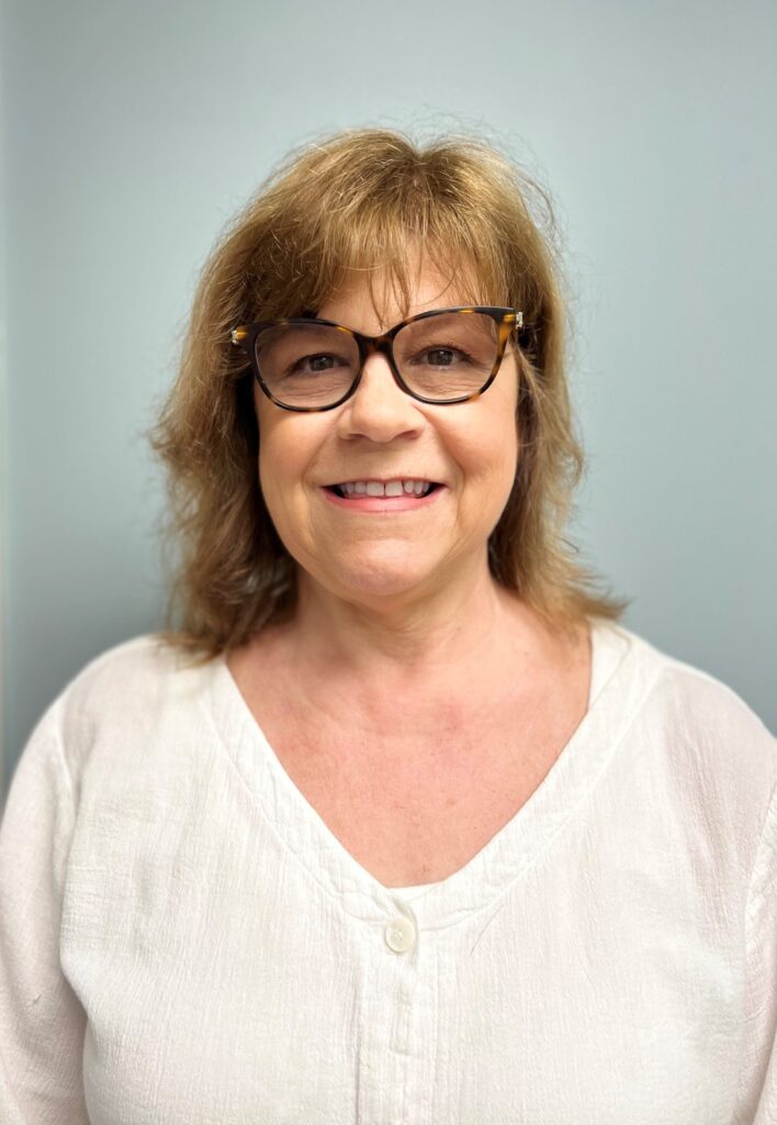 a woman with glasses smiling for the camera