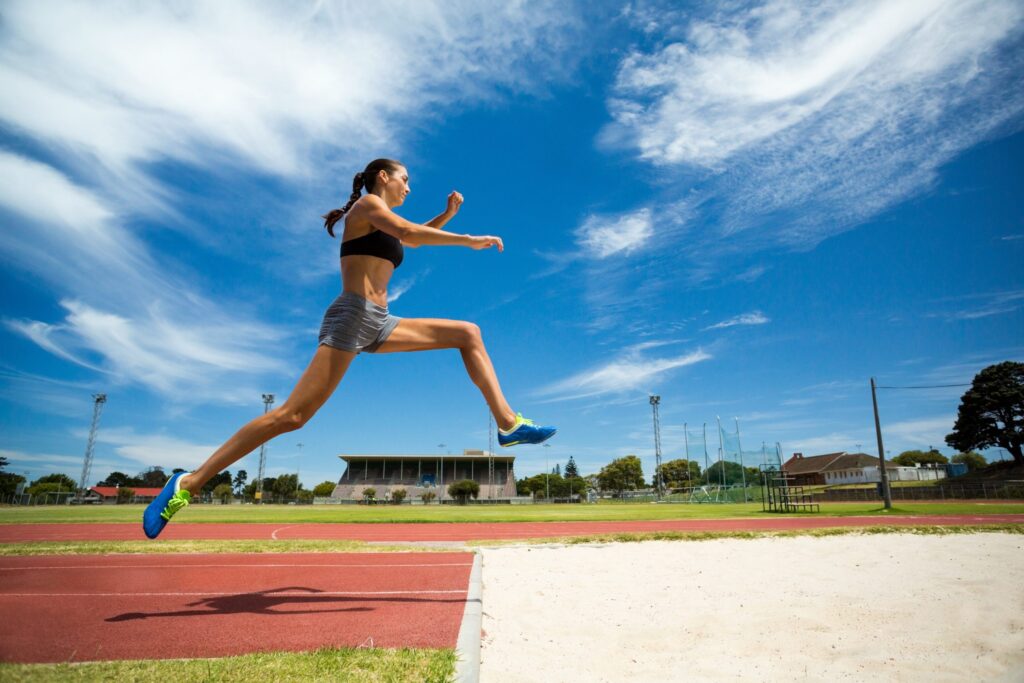 a woman is running on a track in the sun