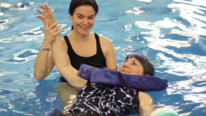 two women in a swimming pool one is holding her arm up