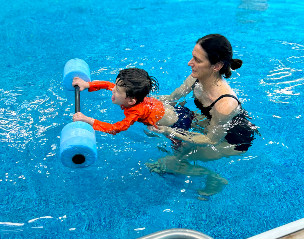 a woman teaching a child how to swim in a pool