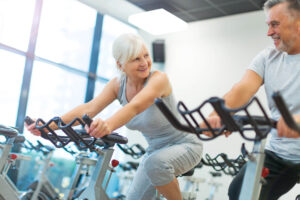 an older couple riding stationary bikes in a gym