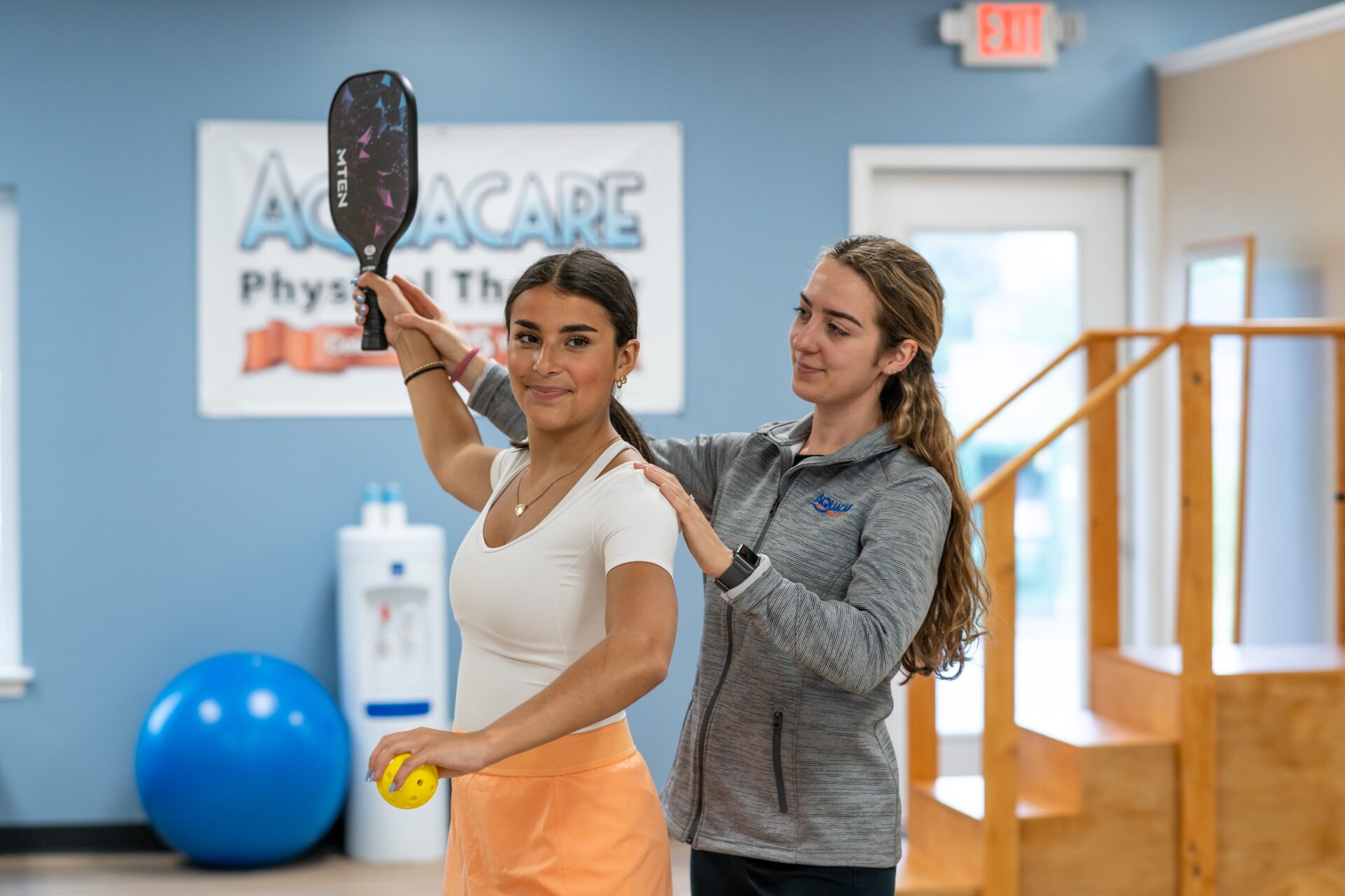 two women holding tennis rackets in a gym