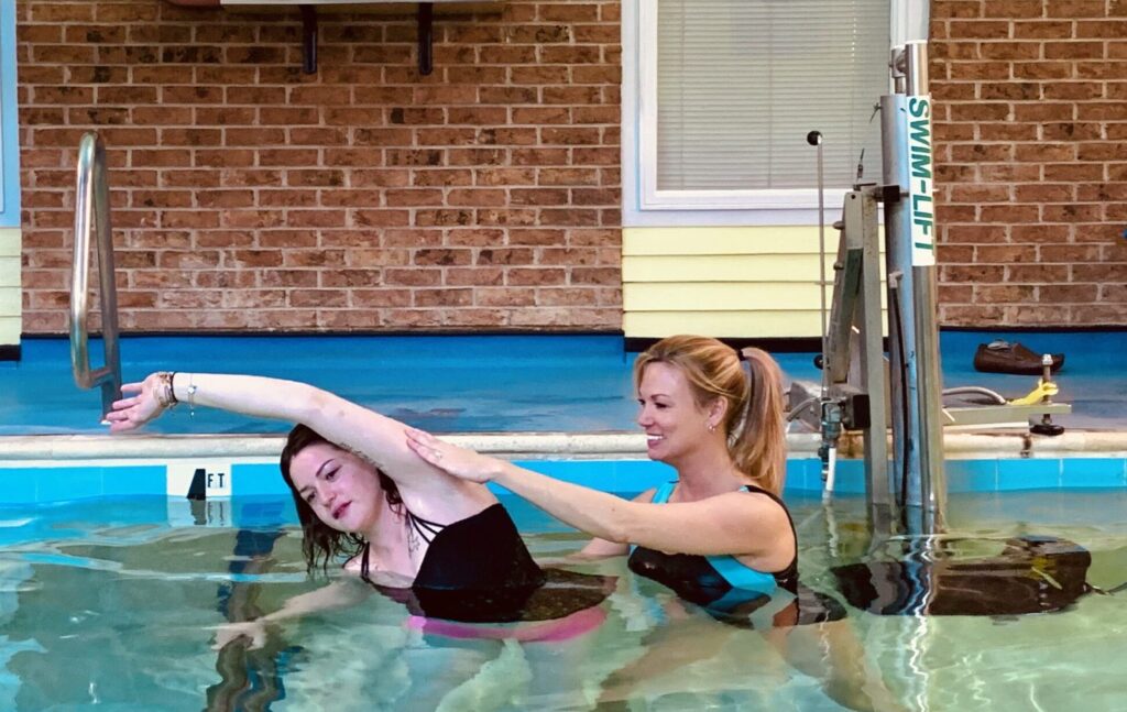 two women in a swimming pool doing exercises