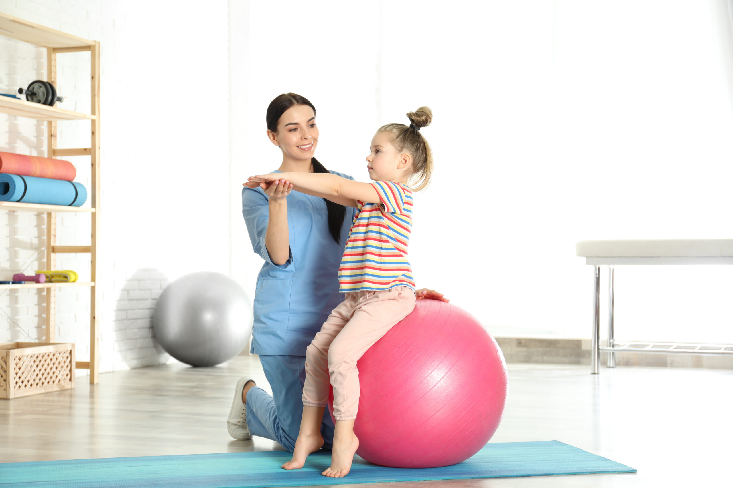 a woman teaching a little girl how to use a ball