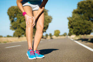 a woman with knee pain on the side of the road