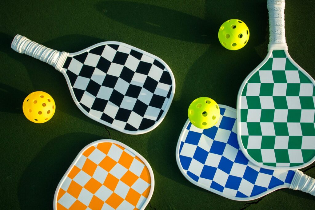 four pickleball paddles and balls on a court