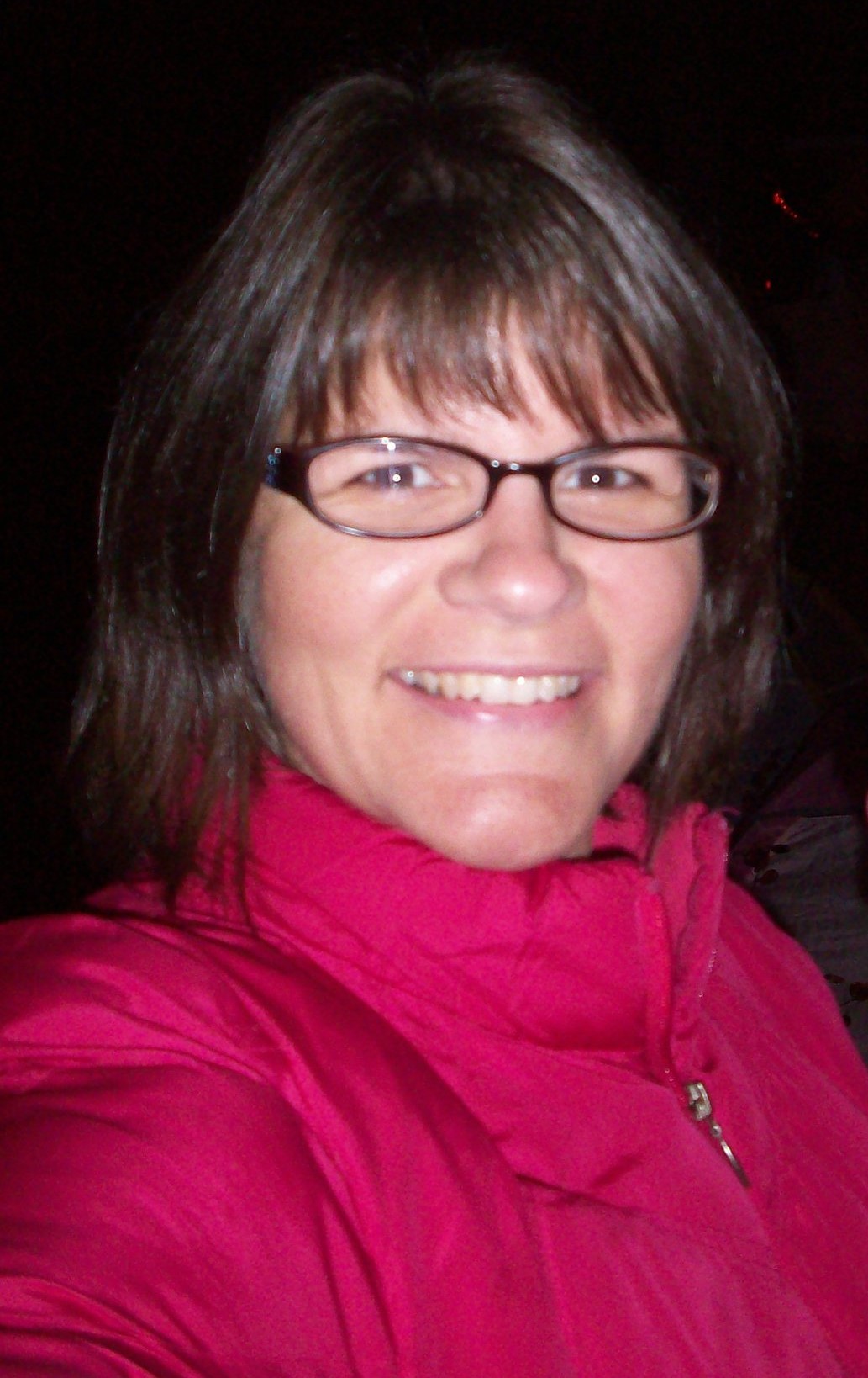 a woman wearing glasses and a pink jacket