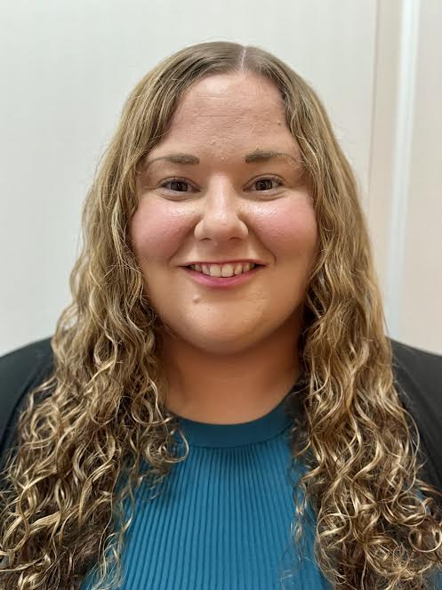 a woman with long curly hair wearing a blue top