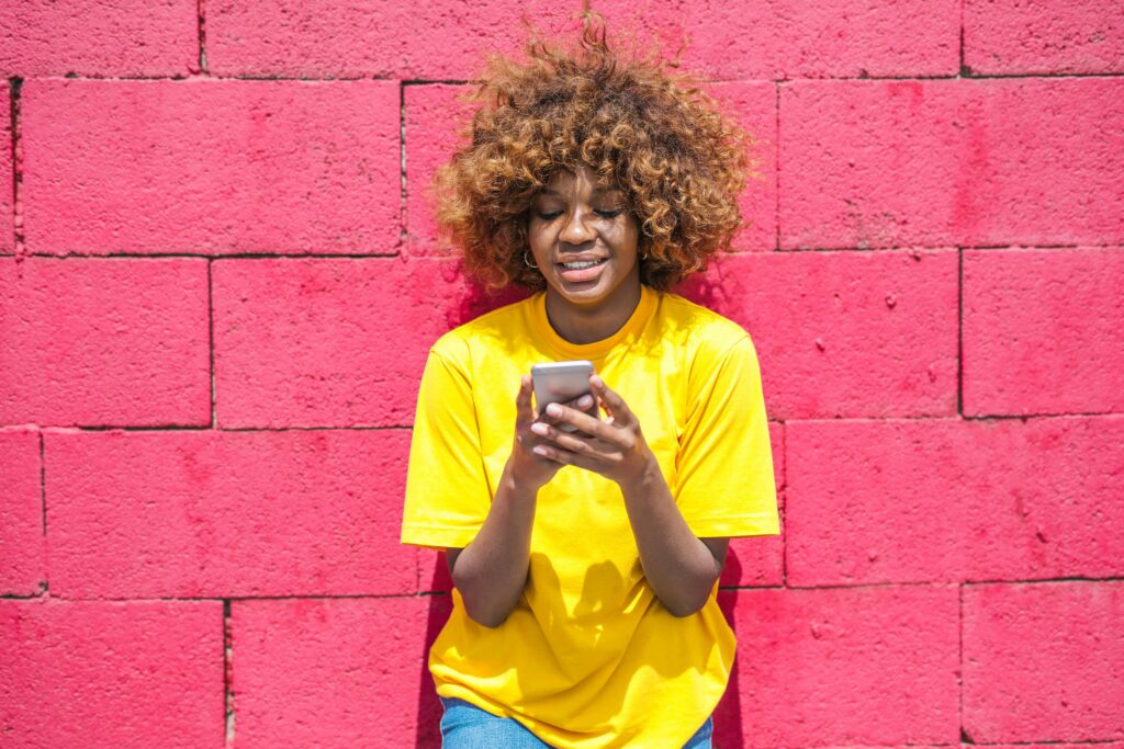 a woman in a yellow shirt using a cell phone